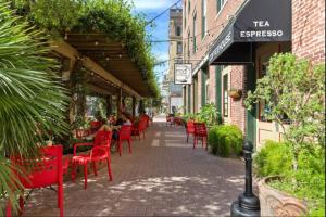 a street with red chairs and people sitting at a restaurant at Historic Downtown Galveston Flat With Game Room in Galveston
