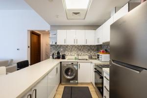 una cucina con mobili bianchi, lavatrice e asciugatrice di Parkside Serenity Stunning Open View 1 bedroom a Mushayrib
