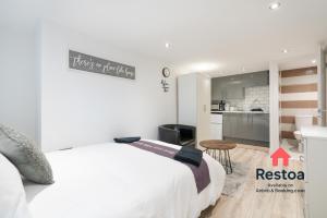 a white bedroom with a bed and a kitchen at Neepsend Lane Studios in Neepsend
