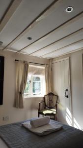 Un dormitorio con una cama y una silla y una ventana. en The Fat Fox, en Pyrton