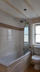 Un baño blanco con bañera y inodoro. en The Fat Fox, en Pyrton