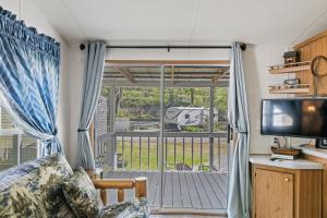 a living room with a sliding glass door to a porch at Tucked Away - Magical Location on the River, Hiking, and Rafting in Dillsboro