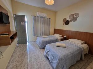 a hotel room with two beds and a television at Casa da Keka em Noronha in Fernando de Noronha