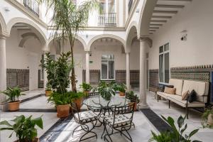 an indoor courtyard with a table and chairs and plants at Apartamentos Gravina 31 in Seville