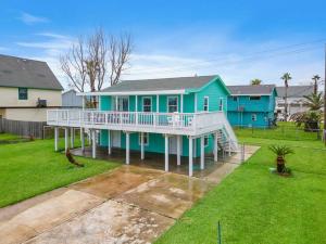ein blaues Haus mit einer weißen Terrasse und einem Garten in der Unterkunft Beach bungalow with large, wrap-around deck, close to beach in Galveston