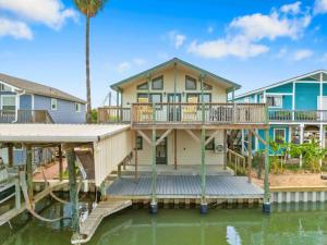 a house with a large deck on the water at Waterfront beach house with the ultimate game room and two docks in Oyster Creek