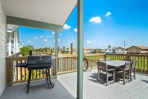 a grill on a deck with a table and chairs at Waterfront beach house with the ultimate game room and two docks in Oyster Creek