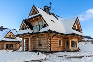 a log cabin with snow on the roof at Jagodowa Osada - domki z balią jacuzzi blisko term in Dzianisz