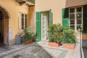 an entrance to a building with green shutters and plants at Studio Apartment 1 Min From Lake in Como