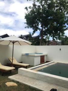 a swimming pool with an umbrella and a table and chairs at Permata Villas Lombok in Kuta Lombok
