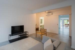 a living room with a couch and a flat screen tv at Figueiras House Pópulo Beach in Ponta Delgada