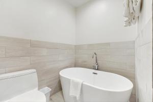a white bathroom with a tub and a toilet at Trent Jones Cottage at Point O' Woods in Benton Harbor