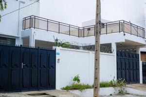 a white house with black gates and a fence at Villa meublée Fidjrossè, Cotonou in Cotonou