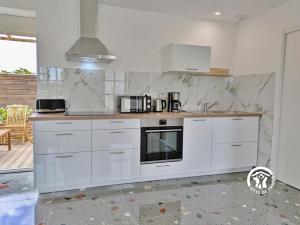 a kitchen with white cabinets and a microwave at La Maison du Bourg, 4 personnes in Louverné
