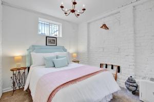 a white bedroom with a bed with a pink blanket at Elsewhere on Madison Square Carriage House in Savannah +25 photos