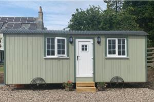a green shed with a white door and windows at Woodhead Shepherds Hut - Sleeps 2 - Mailer Farm in Perth +6 photos