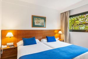 a hotel room with a large bed with blue pillows at Sercotel de los Reyes in San Sebastián de los Reyes +33 photos