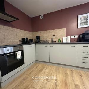 eine Küche mit weißen Schränken und schwarzen Geräten in der Unterkunft Évasion à Hainneville in Cherbourg en Cotentin