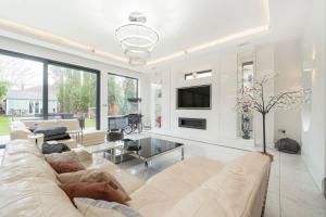 een woonkamer met een bank en een tv bij Exceptional Luxury w Leisure Facilities in Teddington