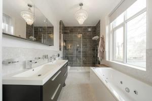 een badkamer met twee wastafels en een bad en een raam bij Exceptional Luxury w Leisure Facilities in Teddington +7 foto's