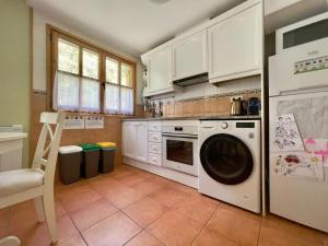 a kitchen with white cabinets and a washer at Dúplex a 20 min de Aigüestortes in Escaló