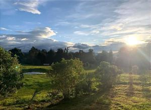 a field with the sun setting in the sky at El valle Muisca in Guasca