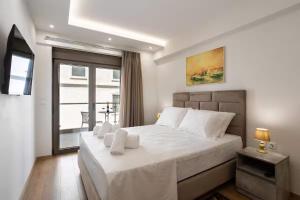 a bedroom with a large white bed with a window at Astir Apartments Kalamata in Kalamata
