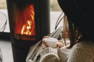 una mujer sosteniendo una taza frente a una chimenea en Apartamenty Moszna - blisko Zamku, Jacuzzi, widok na las, en Moszna