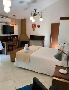 a bedroom with a bed and a desk and a television at Pousada Reserva Penedo in Penedo