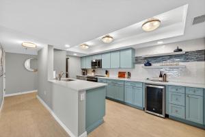 una cocina con armarios azules y encimeras blancas en Renovated direct oceanfront condo with spacious balcony, heated pool, and garage parking, en Ormond-by-the-Sea