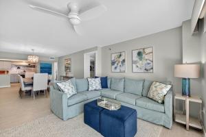 Una sala de estar con un sofá azul y una mesa. en Renovated direct oceanfront condo with spacious balcony, heated pool, and garage parking, en Ormond-by-the-Sea 32 fotos más