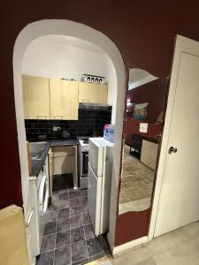 a kitchen with an archway leading into a kitchen with a refrigerator at Cozy Flat near Harrow-on-the-Hill Station in Harrow +5 photos