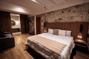 a bedroom with a large bed and a stone wall at Hotel Tabáa Oaxaca in Oaxaca City