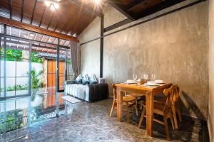 a dining room with a wooden table and a couch at Weda Ubud by Madhava Villas in Ubud