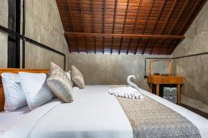a bedroom with a bed with a chair and a table at Weda Ubud by Madhava Villas in Ubud