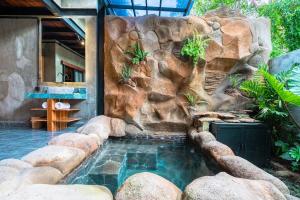 a swimming pool with a rock wall next to a swimming pool at Weda Ubud by Madhava Villas in Ubud