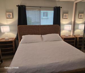 a bedroom with a large bed with two lamps on tables at Cozy island apartment in Pompano Beach +23 photos