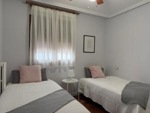 two beds in a white room with a window at 18 Torres Pasaje de los Giles in Zaragoza