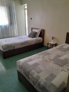 two beds sitting in a bedroom with a window at Casa maartil in Martil