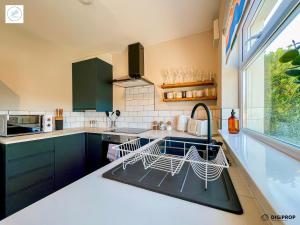 cocina con armarios azules, fregadero y ventana en Alder House - Dowlais, en Dowlais