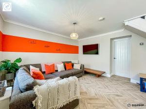 a living room with a couch and orange accent wall at Alder House - Dowlais in Dowlais