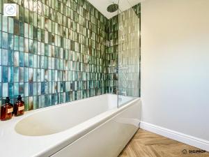 a bath tub in a bathroom with a tile wall at Alder House - Dowlais in Dowlais +21 photos