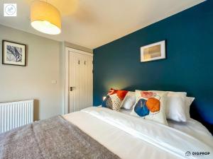 a bedroom with a blue wall and a bed with pillows at Alder House - Dowlais in Dowlais