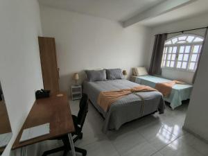 a bedroom with a bed and a desk and a window at Estadia Férias e Trabalho in Vila Velha