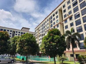 ein großes weißes Gebäude mit einem Tennisplatz davor in der Unterkunft Willow Whisper 3 ROOMS by EZYHOME MELAKA in Ayer Keroh