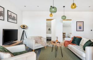 a living room with white furniture and a flat screen tv at Le Rooftop Loft premium 3 chambres avec terrasse & parking en centre-ville de Saint-Étienne in Saint-Étienne