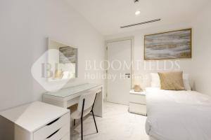 Habitación blanca con escritorio y cama en Bloomfileds Memorable 2br Duplex Masdar City, en Abu Dhabi Intl 16 fotos más