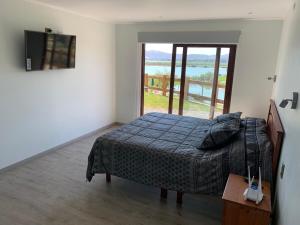 a bedroom with a bed and a large window at Casa con vista lago Rapel in Las Cabras