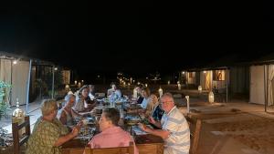 a group of people sitting at a table eating food at Merzouga Heart Luxury Camp in Merzouga