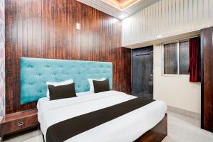 a bedroom with a large bed with a blue headboard at Hotel O Divya in Bilāspur